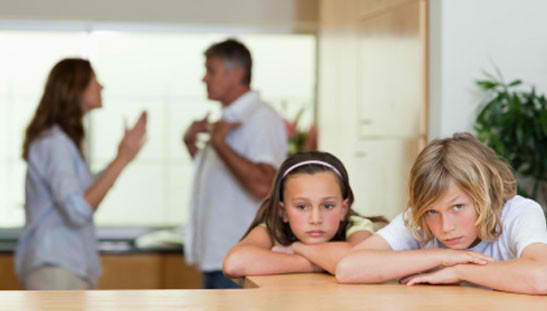 Children looking sad while parents argue in background