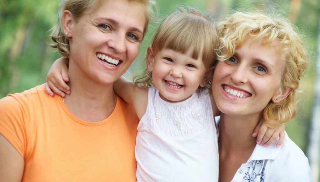 Two mothers hugging daughter
