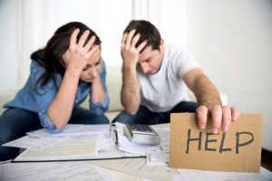 Couple looking stressed looking at paperwork and holding help sign