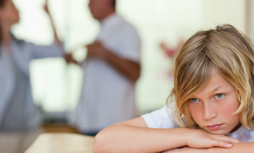 Child looking sad with parents arguing in the background