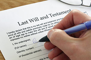 Hand signing paper saying "Last Will and Testament"