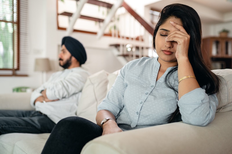 Man and woman sitting on opposite ends of the couch looking upset