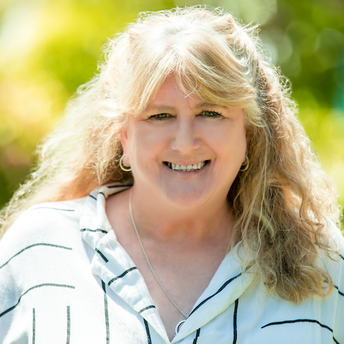 Smiling woman with curly blonde hair in a striped shirt, representing the compassionate team at Rafton Family Lawyers in Sydney, specializing in family and divorce law.
